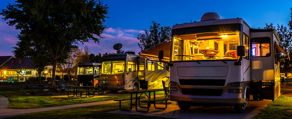 Row of RVs parked at a campground during dusk - www.jjinsure.com/
